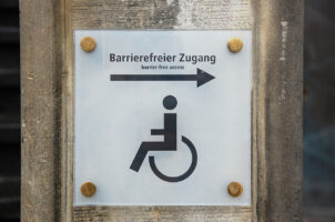 Ein Schild mit einem Rollstuhl, Pfeil und Satz Barrierefreier Zugang