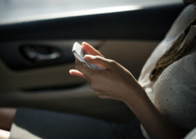 Haende halten ein Handy im Auto