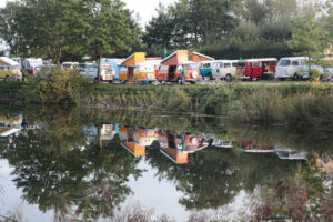 Eine Ansammlung von VW Bullis an einem Fluss