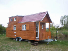 Ein Anhaenger mit einem Tiny House mit einem Spitzdach