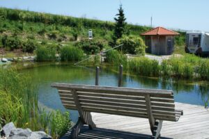 Eine Bank an einem Teich vom Luxuscampingplatz Dreiquellenbad
