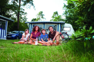 Eine Familie vor ihrem Camper auf dem Suedsee Campingplatz einem Luxuscampingplatz in Deutschland