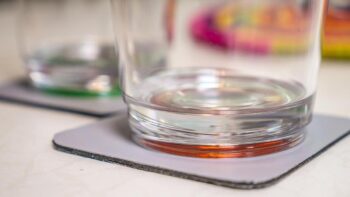 Ein Wasserglas mit buntem Boden auf einem Magnetuntersetzer der das Glaeser verrutschen verhindert