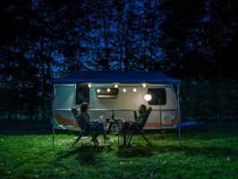 Ein Paar vor dem Wohnwagen im Licht von Outdoorleuchten als Lampions