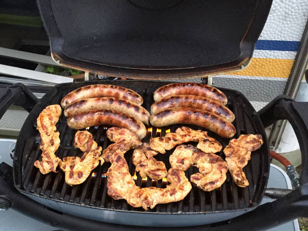 Großer Ratgeber: der perfekte Camping-(Gas)-Grill 5 Würstchen und Hühnchen auf dem Gasgrill