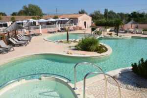 Camping Les Fontaines Poolanlage mit Liegestuehlen und Sonnenschirmen
