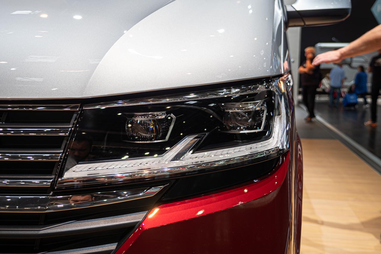 VW California 6.1 – Strand-Hopping mit Stil (inkl. Video-Roomtour) 15 Nahaufnahme des linken Frontscheinwerfers vom VW California 6.1 Beach Camper auf dem Messestand des Caravan Salon 2019 in Düsseldorf