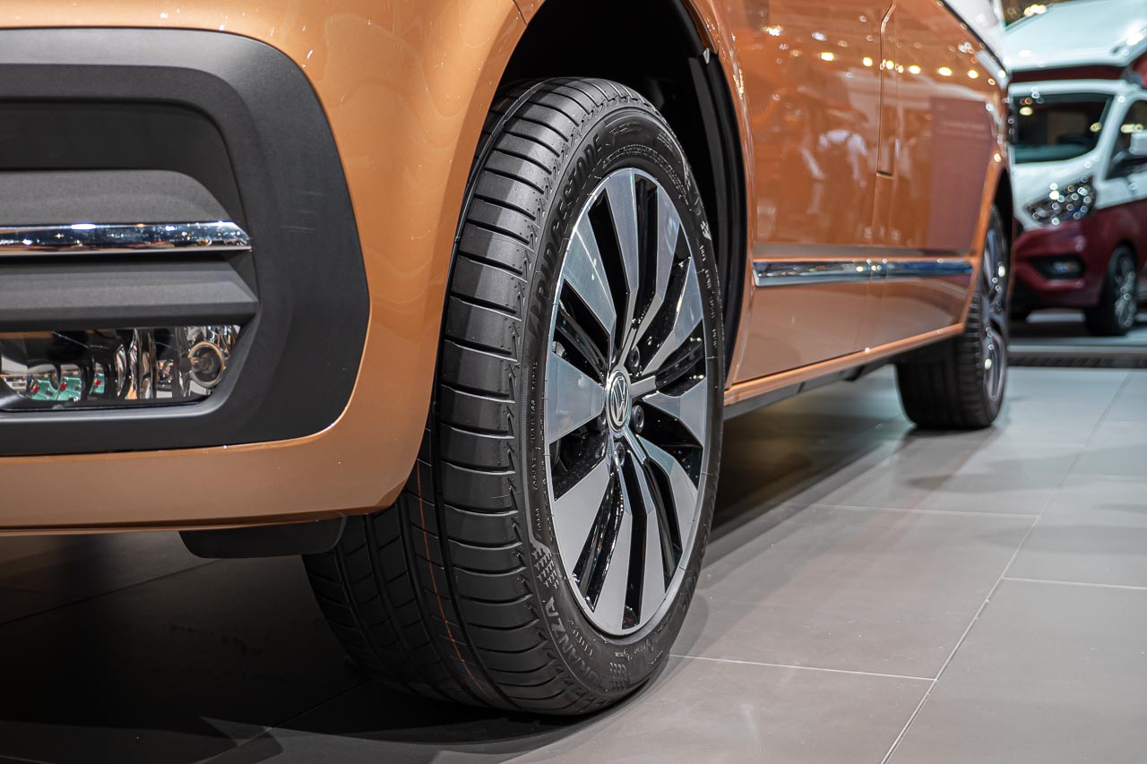 VW California 6.1 – Strand-Hopping mit Stil (inkl. Video-Roomtour) 17 Nahaufnahme von vorne seitlich von einem linken Vorderreifen eines VW California 6.1 Oceanauf dem Messestand des Caravan Salon 2019 in Düsseldorf