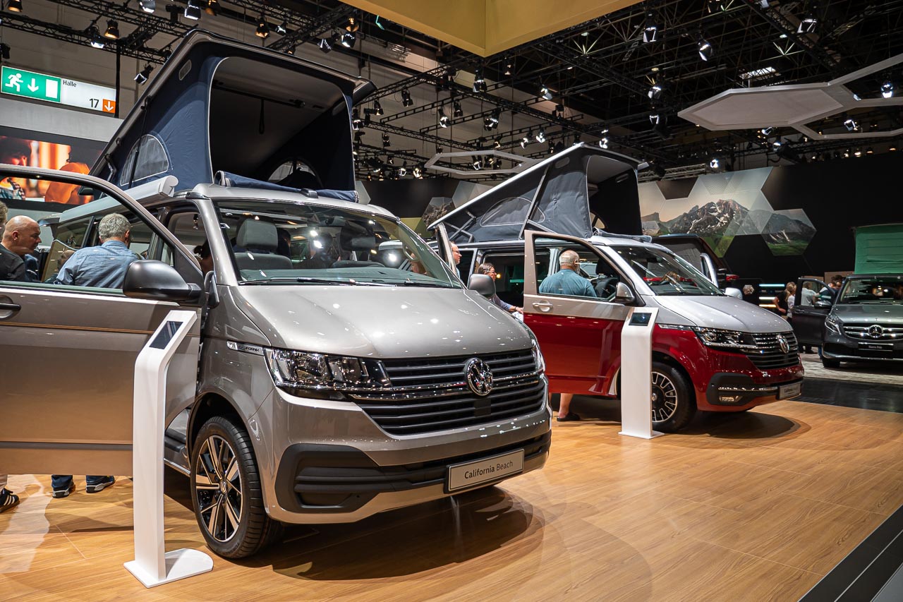 VW California 6.1 – Strand-Hopping mit Stil (inkl. Video-Roomtour) 18 Blick von vorn auf einen VW California 6.1 Beach mit offenen Türen und aufgestelltem Hochdach auf dem Messestand des Caravan Salon 2019 in Düsseldorf