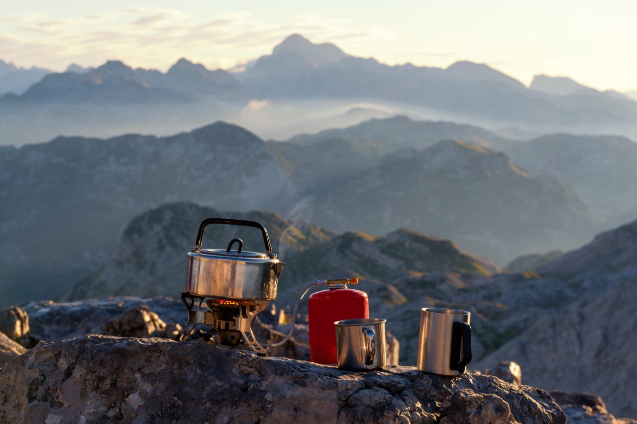 Gaskocher mit Töpfen steht auf einem Felsen mit Ausblick auf Berge
