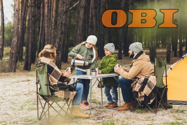 Familie sitzt auf Campingstühlen an Campingtisch vor einem Zelt im Wald; Oben links: Logo von OBI