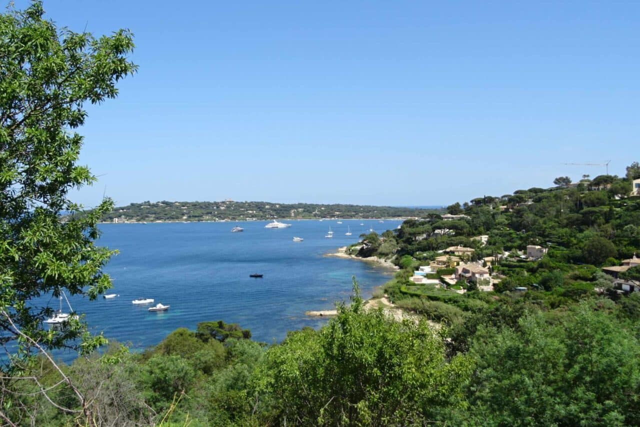 Blick auf eine der Buchten von Saint-Tropez mit den davor liegenden Yachten und den Villen in der Hügellandschaft.