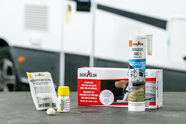 Alt Text: Camper Aufbau mit Klebstoffen und Solar-Modulen auf einem Campingplatz.