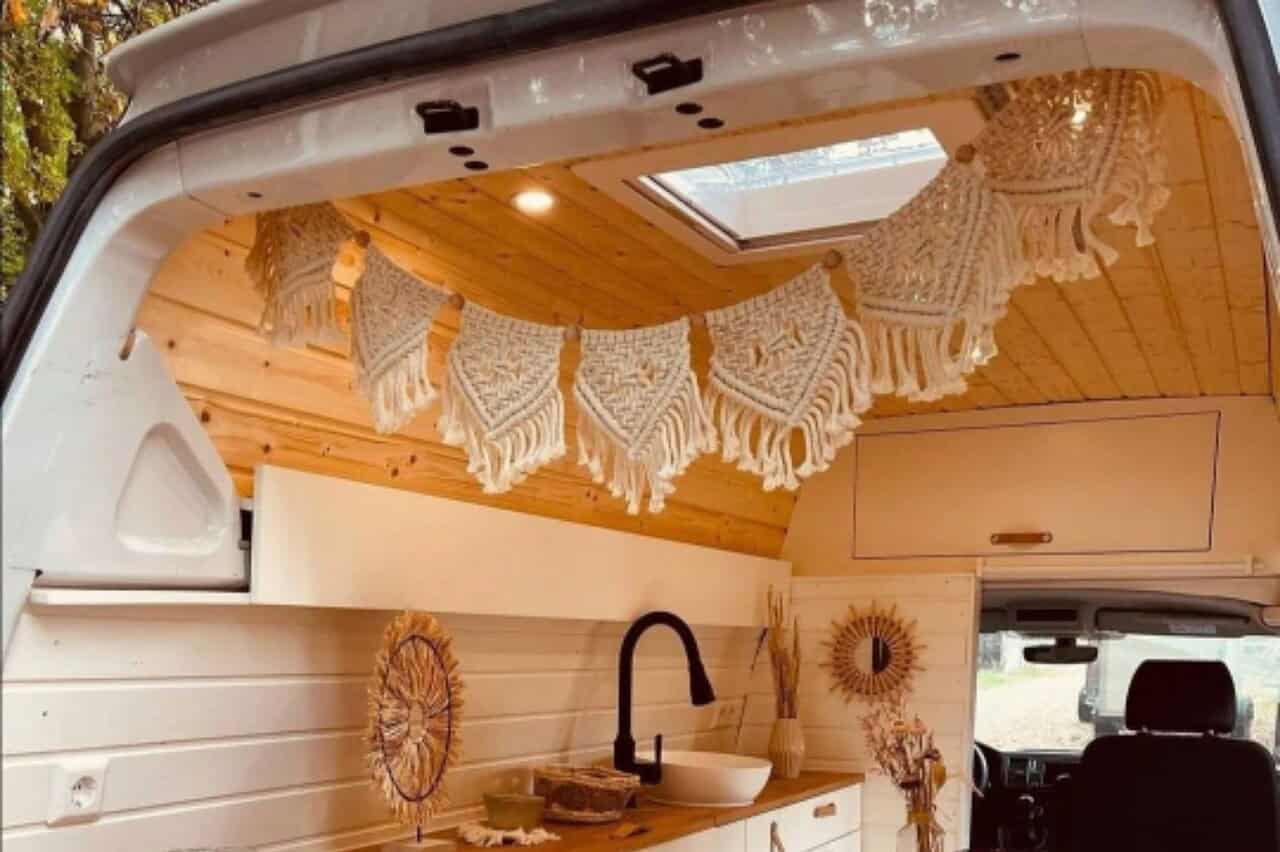 5 Last-Minute-Weihnachtsgeschenke für Camper 5 Helle, moderne Camperküche mit Holzinterieur, Makramee-Dekoration und Dachfenster für Licht und Luft.