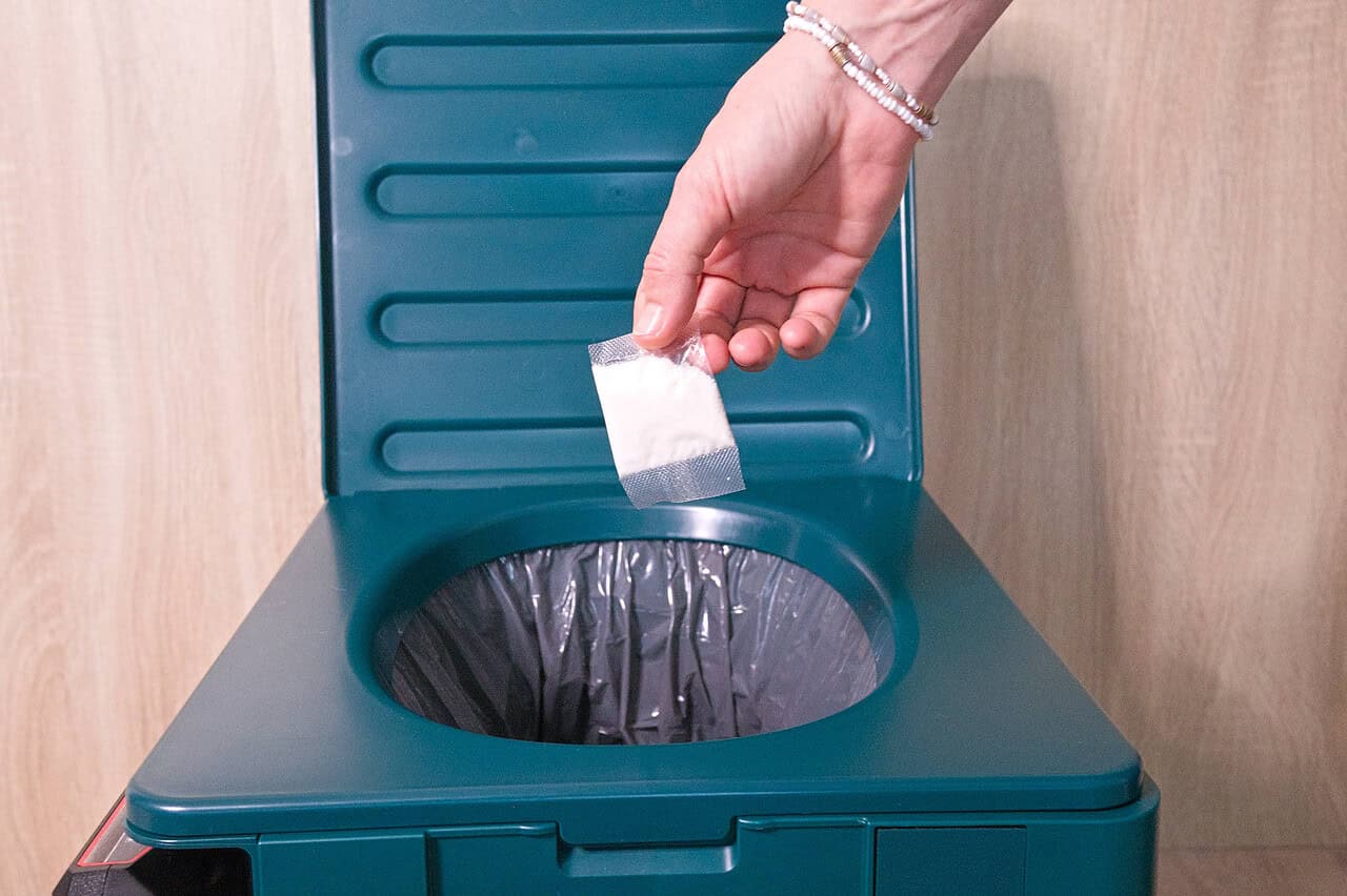 Nie wieder Schwarzwasser und Entsorgungsstationen: Die mobile Verschweißtoilette Clesana X1 im Test 11 Nahaufnahme einer hand, die Kaffeepulver in einen kleinen Papierbeutel gibt.